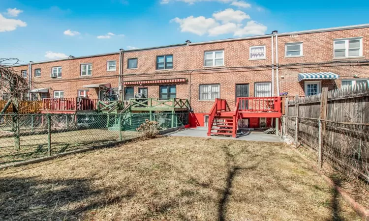 Back of house with a yard, a fenced backyard, and brick siding