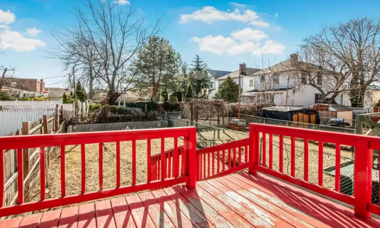 Wooden deck featuring a yard, a residential view, an outbuilding, and a fenced backyard