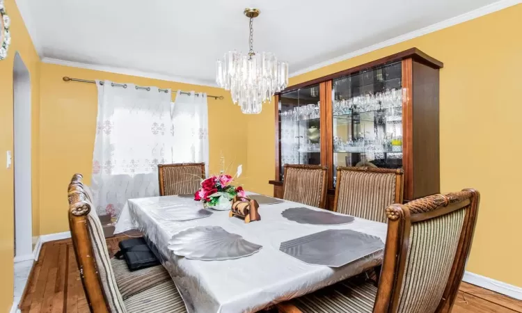 Dining space with an inviting chandelier, crown molding, baseboards, and wood finished floors