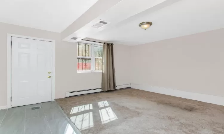 Empty room featuring baseboards, visible vents, and baseboard heating