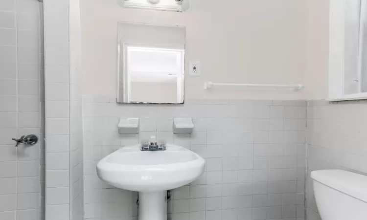 Bathroom with toilet, tile walls, and wainscoting