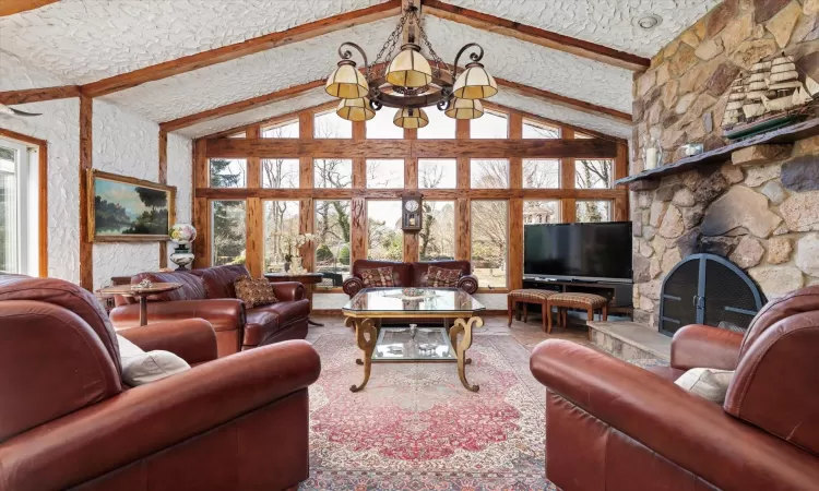 Living room featuring beamed ceiling, plenty of natural light, high vaulted ceiling, and a textured ceiling