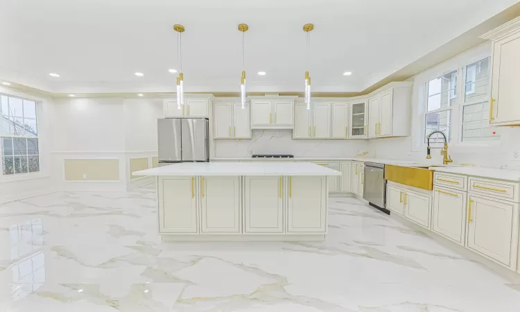 Kitchen with appliances with stainless steel finishes, a kitchen island, a wealth of natural light, and pendant lighting