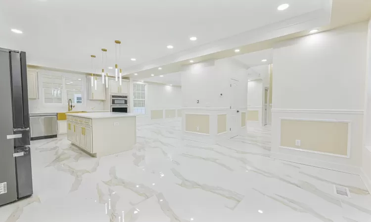 Kitchen with white cabinets, sink, decorative light fixtures, a kitchen island, and stainless steel appliances