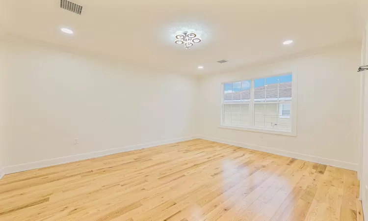 Spare room with crown molding and light wood-type flooring