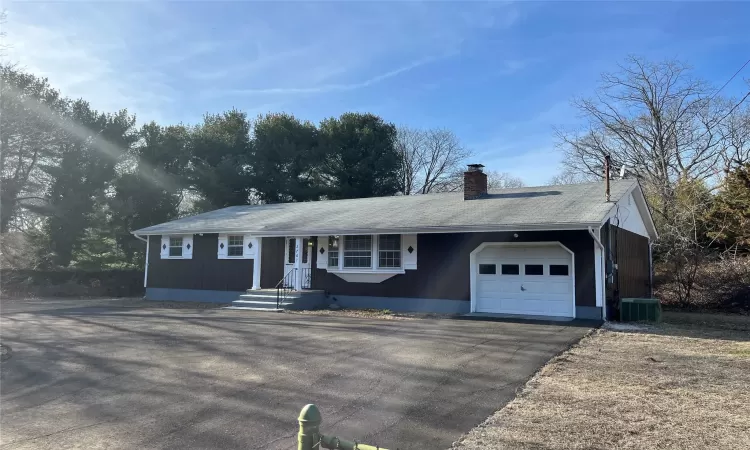 Ranch-style home with aphalt driveway, a garage, central AC unit, and a chimney