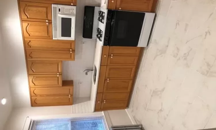 Kitchen with light countertops, range, marble finish floor, and a sink