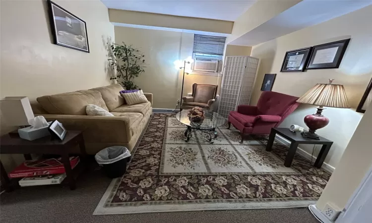 Carpeted living room featuring cooling unit and baseboards