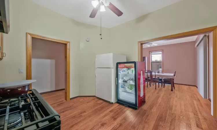 Kitchen featuring range with gas cooktop, baseboards, light wood-style flooring, freestanding refrigerator, and a ceiling fan