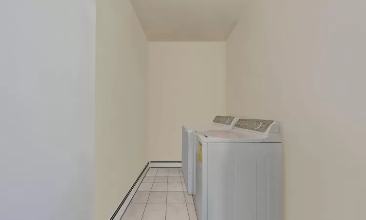 Laundry room featuring independent washer and dryer, light tile patterned flooring, and laundry area