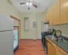 Kitchen featuring stainless steel gas range oven, a ceiling fan, under cabinet range hood, freestanding refrigerator, and light wood-style floors