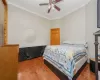 Bedroom with ornamental molding, ceiling fan, and wood finished floors