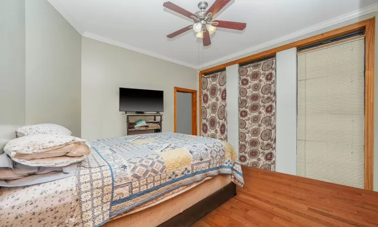 Bedroom with a ceiling fan, wood finished floors, and ornamental molding