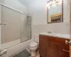 Full bathroom with tile patterned floors, toilet, tile walls, bath / shower combo with glass door, and vanity