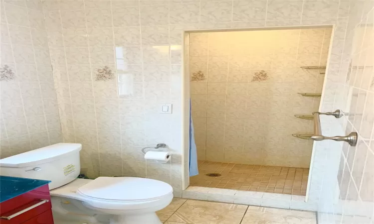 Full bath, a stall shower, tile patterned floors and tile wall.