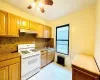 Kitchen featuring a ceiling fan, radiator heating unit, white gas range oven, under cabinet range hood, and tasteful backsplash