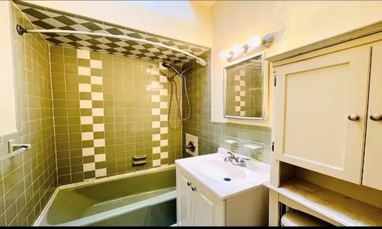 Bathroom with vanity, tile walls, tub / shower combination, and backsplash