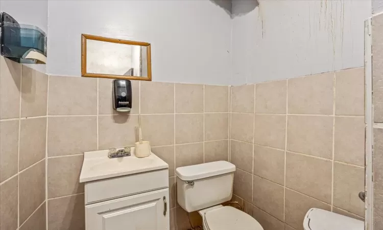 Half bathroom with vanity, tile walls, and toilet