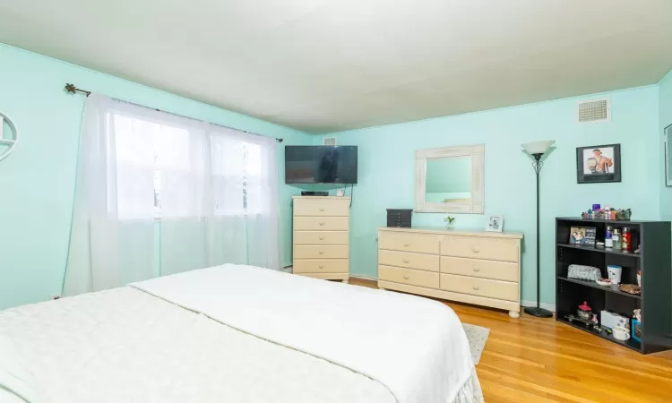 Bedroom with light wood-type flooring, visible vents, and baseboards