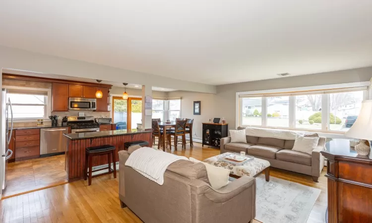 Living area featuring a baseboard radiator, light wood-style floors, visible vents, and a toaster