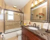 Bathroom featuring bath / shower combo with glass door, toilet, vanity, tile patterned floors, and tile walls