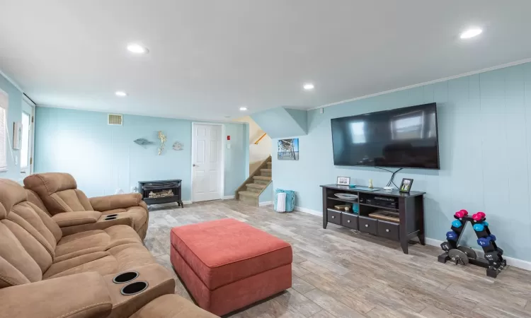 Living area featuring visible vents, wood finished floors, stairs, recessed lighting, and a wood stove