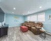 Living room featuring baseboards, ornamental molding, baseboard heating, recessed lighting, and wood finished floors