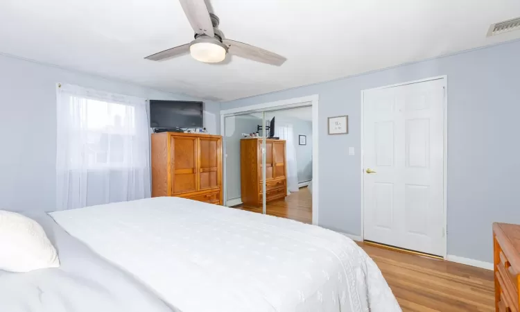 Bedroom featuring a ceiling fan, visible vents, wood finished floors, baseboards, and a closet