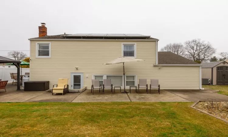 Back of property featuring a shed, a chimney, a yard, an outdoor structure, and a patio area