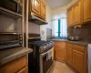 Kitchen with light tile patterned floors, stainless steel appliances, under cabinet range hood, dark countertops, and tasteful backsplash