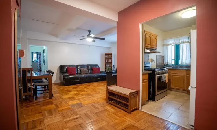 Living room featuring beam ceiling and a ceiling fan