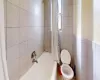 Bathroom with toilet, tile walls, and shower / tub combo with curtain