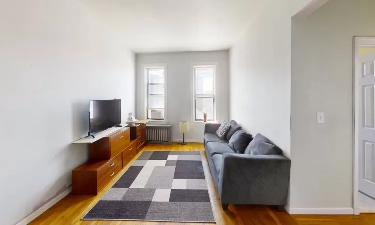 Living room featuring radiator, baseboards, and light wood-type flooring