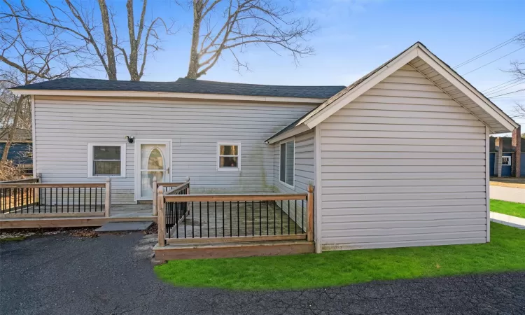 Back of house featuring a deck and a shingled roof