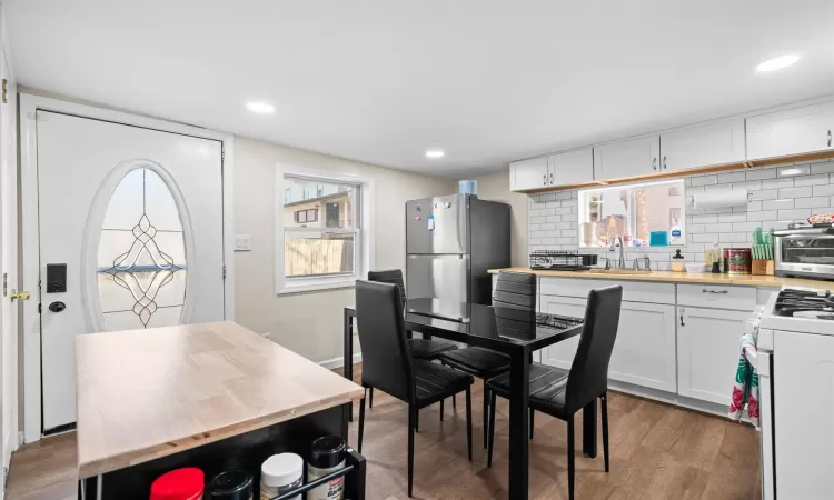 Kitchen featuring wood finished floors, white range with gas cooktop, white cabinets, and freestanding refrigerator