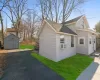 View of home's exterior with a yard, an outbuilding, a storage shed, and a shingled roof